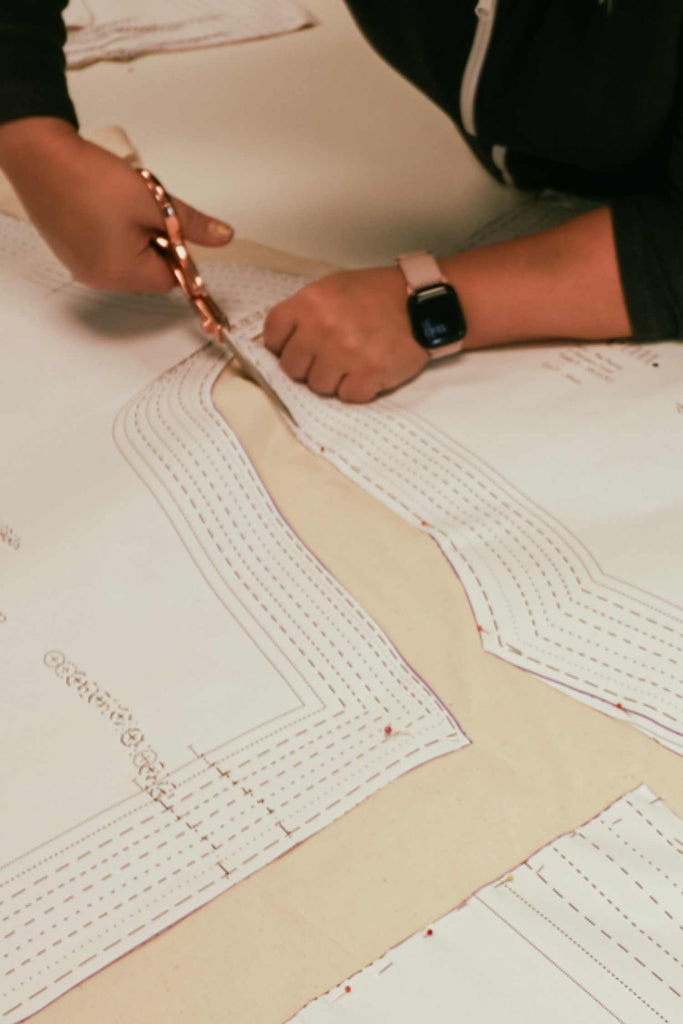 Leim Sewing Workshops - Jumpsuit Sewing Workshops - a white woman is cutting out the pattern with copper coloured scissors on toile fabric