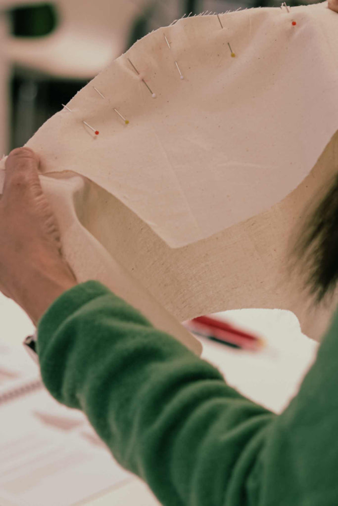 Leim Sewing workshops - jumpsuit sewing workshops - Person holding a piece of fabric with pins on it, wearing a green sleeve.