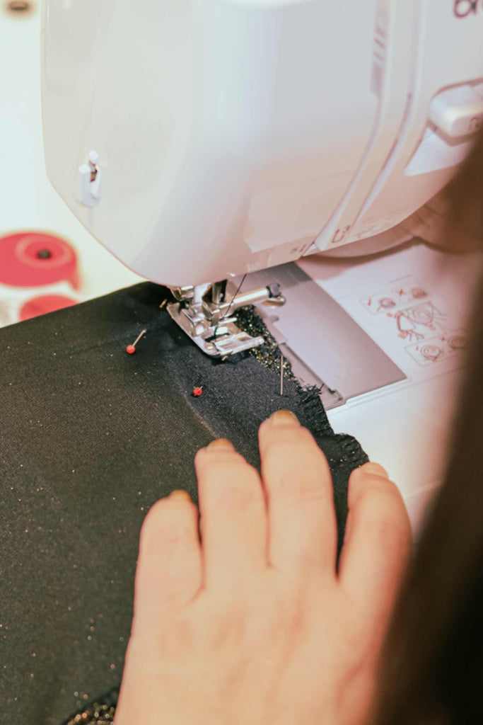 Leim Sewing workshops - jumpsuit sewing workshops - Close-up of a sewing machine in use with a hand guiding fabric.