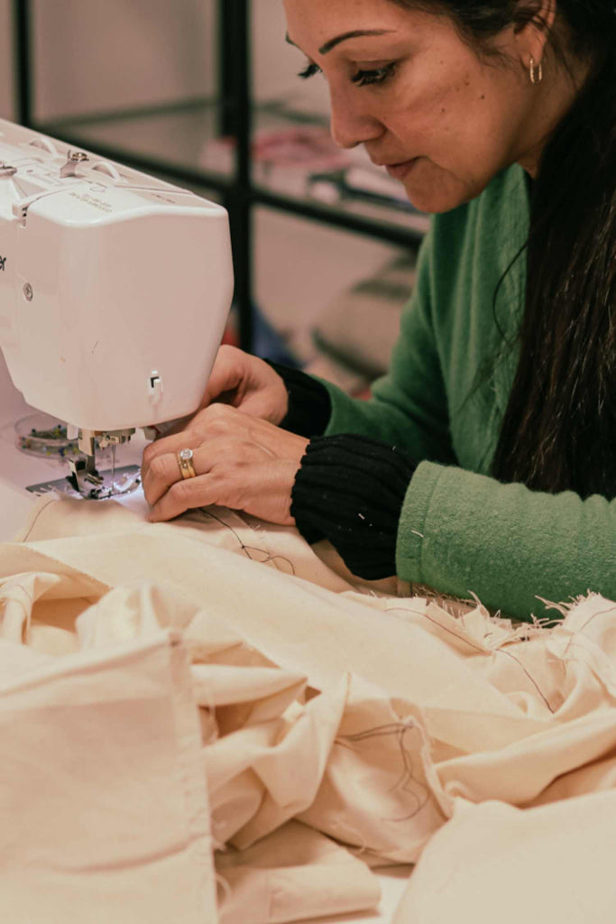 Woman working on a sewing machine with fabric in a workshop setting